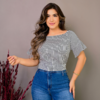 Mulher sorridente usando blusa listrada preta e branca e jeans, com cabelo solto e brincos grandes, posando em fundo neutro.