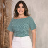 Mulher sorrindo usando blusa listrada verde e branca com mangas largas, em frente a um fundo neutro.