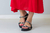 Sandálias Papete Shine Stone em preto com detalhes prateados, usadas com vestido vermelho.