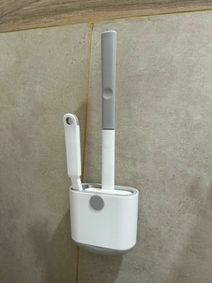 Escobilla siliconada con cepillo blanco colgada en pared de baño con soporte a juego