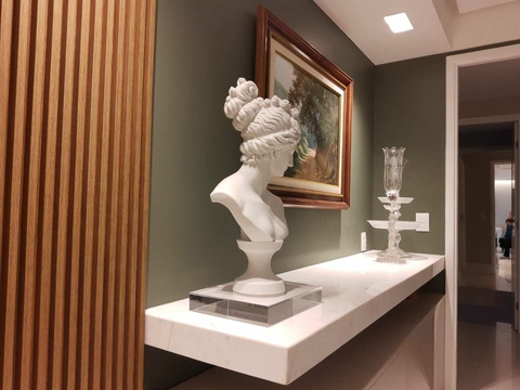 Busto de escultura branca sobre uma base, decorando uma prateleira em um ambiente moderno.