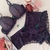 Conjunto de lingerie com sutiã com bojo e duas calcinhas em renda roxa, decorado com laços verdes.