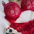Conjunto de lingerie de renda na cor vermelha, composto por sutiã e duas calcinhas. A peça apresenta detalhes em renda e está acompanhada de produtos de maquiagem.