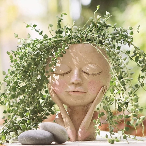 Cachepot que parece ter vida, traz menina imersa em suas ideias . Vaso cachepô de menina garota com as mãos no rosto pensando pensativa de olhos fechados sonhando . Decoração nórdica atual e moderna . 