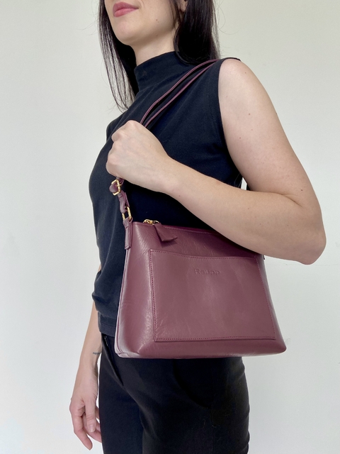 Modelo segurando a bolsa Lena Crossbody na cor jaboticaba, com alças finas e design elegante.