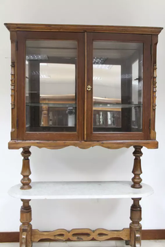 CRISTALEIRA QUARTEIO, ESTILO COLONIAL, EM VINHÁTICO, DUAS PORTAS EM VIDRO,BASE CENTRAL EM MÁRMORE CARRARA BRANCO - CÓD. 50