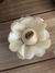 White flower-shaped decoration with golden edges and a central bead, showcased on a wooden surface.