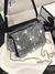 Bolsa cuadrada con diseño de diamantes y cadena.