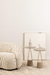 Mesa lateral Lilly com base em concreto ao lado de um sofá claro, decorada com estatuetas em um ambiente minimalista.