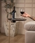 Mesa lateral Clip na cor vinho com garrafa de vinho e taça, ao lado de um sofá.
