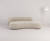 Sofá Sintonia em tom claro com design curvo, localizado em um ambiente minimalista.
