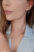 Modelo usando brinco coração cravejado banhado a ouro 18k, com colares delicados e um estilo elegante.