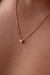 Colar Ponto de Luz Yasmin banhado a ouro 18k, com detalhe em pedra brilhante, posicionado sobre a pele.