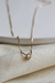 Colar Ponto de Luz Yasmin em ouro 18k com detalhe de pedra brilhante, sobre tecido claro.