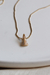 Colar cravejado em ouro 18k com pingente da imagem de Aparecida, em fundo claro.