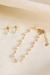 Conjunto de pérolas infantis com brinco e corrente banhados a ouro 18k sobre fundo claro.