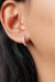 Brinco argola clara cravejado com microzirconias em prata 925, usado na orelha de uma mulher.