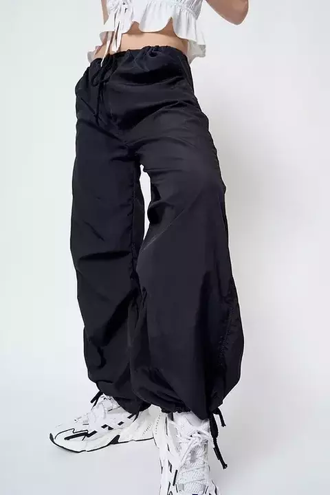 Pantalón parachute negro con ajuste en la cintura, combinado con zapatillas blancas.
