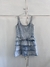 Vestido Ossira de denim azul claro con tirantes anchos y volantes en la parte inferior, colgado en una percha frente a un fondo blanco.