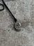 Collar con un colgante en forma de caracol plateado sobre un fondo de superficie gris.