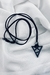 Colar Splendor com pingente de triângulo vazado, cordão de camurça e berloque geométrico, perfeito para looks modernos e elegantes.