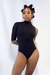 Body assimétrico preto, feito de malha de montaria, com uma manga três quartos, faixa lateral transparente e zíper nas costas. Gola alta, com visual tecnológico e futurista.