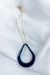 Um colar de design exclusivo, com um pingente de cerâmica azul profundo suspenso em uma corrente folheada a ouro. A peça é elegante e minimalista, perfeita para expressar sua individualidade e estilo autoral. Use-o com confiança e deixe sua criatividade b
