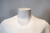 Camiseta branca com textura trançada, exibida em um manequim.
