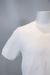 Camiseta branca com textura trançada, destacando detalhes das mangas e do colarinho.