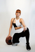 Modelo vestindo legging preto e branco, agachada com uma bola de basquete.