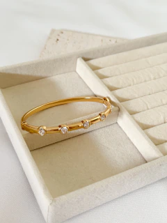 Bracelete dourado com cinco pedras brilhantes em caixa de veludo bege