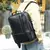 Pessoa usando uma mochila de couro preta para notebook de 15.6 polegadas em ambiente externo, destacando o design premium.