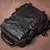mochila para notebook preta AllBlack exibida sobre uma superfície marrom. A mochila tem alças robustas, fechos em metal e costuras reforçadas, destacando sua durabilidade e qualidade artesanal. Ideal para uso diário e viagens, ela combina estilo e funcion