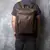 Homem usando mochila de couro legítimo marrom estilo vintage com bolso frontal organizador e alças acolchoadas.
