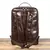 Mochila de Couro Para Notebook Café Uni 6887 Espaço para Notebook 15.6 Polegada, vista da parte de traz da mochila com as alças macias e ajuste em metal cromado, a mochila esta sobre um piso de madeira com um fundo branco