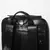 Detalhe superior de Mochila Masculina de Couro Preta Retrô com alças ajustáveis, alça de mão e gancho metálico.