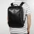 Mochila masculina de couro preta retrô multifuncional sendo usada para transporte seguro de notebook de 15.6 polegadas.