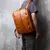 Homem usando mochila masculina de couro legítimo castanho retrô multifuncional para notebook de até 15.6 polegadas.