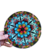Prato decorativo de vidro com design de mandala colorida, medindo 21 cm, sendo segurado por uma mão.