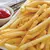 Prato com batatas palito fritas e um recipiente de ketchup ao lado.