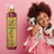 Frasco de shampoo Esmeralda Cereja e Avelã da Dolce Pet, com uma mulher segurando dois cachorrinhos ao fundo.