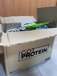 Caja de cartón abierta con bolsas de Whey Protein Star Nutrition dentro, en el interior de una habitación con piso de baldosas