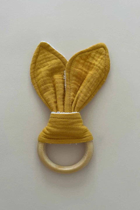 Mordedor sensorial montessoriano com anel de madeira natural e tecido amarelo em formato de orelhinhas, ideal para bebês em fase de dentição.