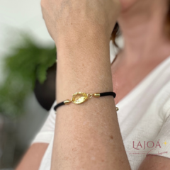 Pulseira cordão com pingente em forma de gota, destacando-se em um braço feminino.
