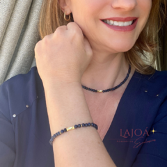 Modelo usando um conjunto de colar e pulseira de sodalita, com detalhes em dourado.