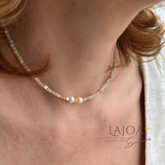 Colar choker de rodonita rosa com detalhes em ouro e pérolas, usado ao redor do pescoço.