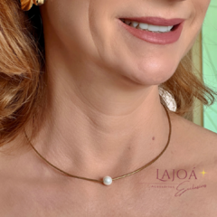 Detalhe do colar de hematitas com uma pérola, apresentado no pescoço de uma mulher.