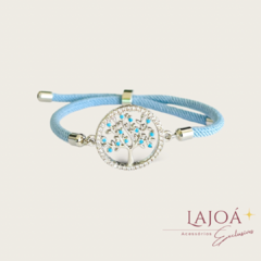 Pulseira cordão com pingente em formato de árvore da vida, adornada com pedras azuis e detalhes em prata.