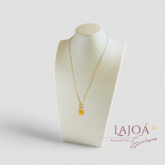 Colar de corrente fina banhado a ouro com pingente de citrino, exibido em um suporte elegante.