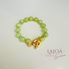Pulseira de pedras verdes com fecho dourado em destaque.
